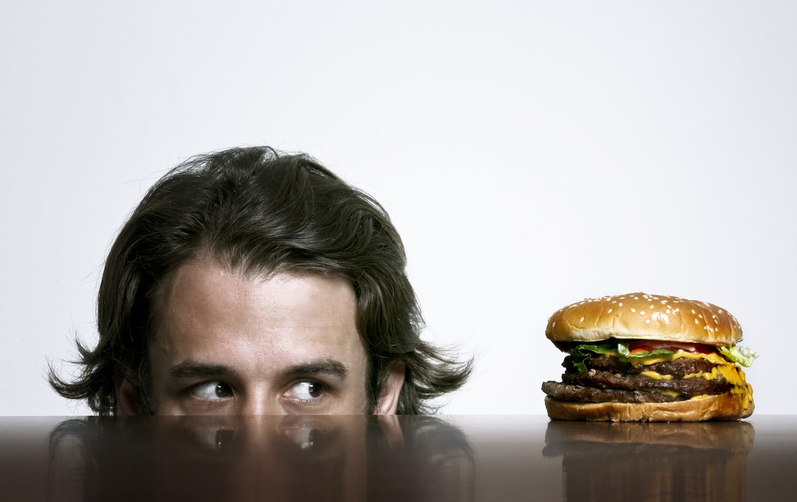 Целый голодный. Мужчина с гамбургером. Человек ест бургер. Человек ест гамбургер.